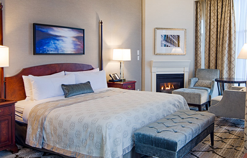 Cozy room with queen size bed next to electric fireplace, large foor to ceiling windows.